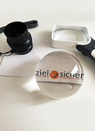 Eine Auswahl von optischen Hilfsmitteln, die das Logo von ziel-sicher vergrößern Eine Auswahl von optischen Hilfsmitteln, die das Logo von ziel-sicher vergrößern